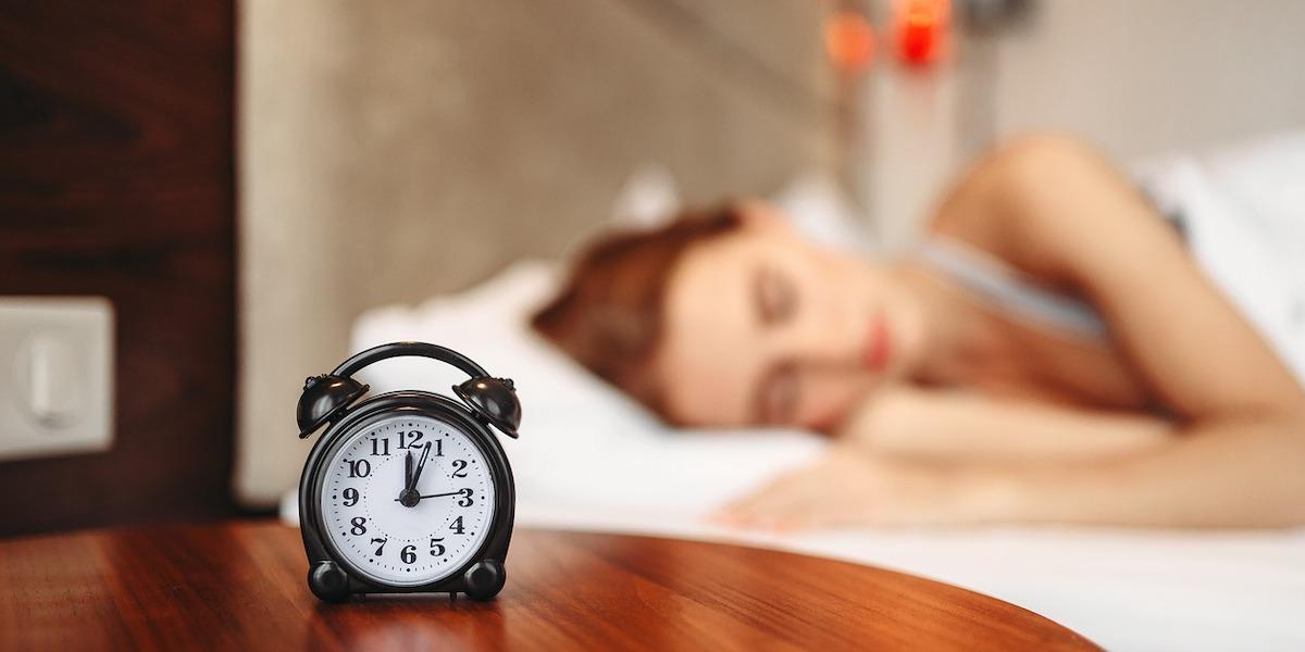 En kvinna sover med en väckarklocka på nattduksbordet, att titta på klockan om du vaknar under natten, kan störa din sömn