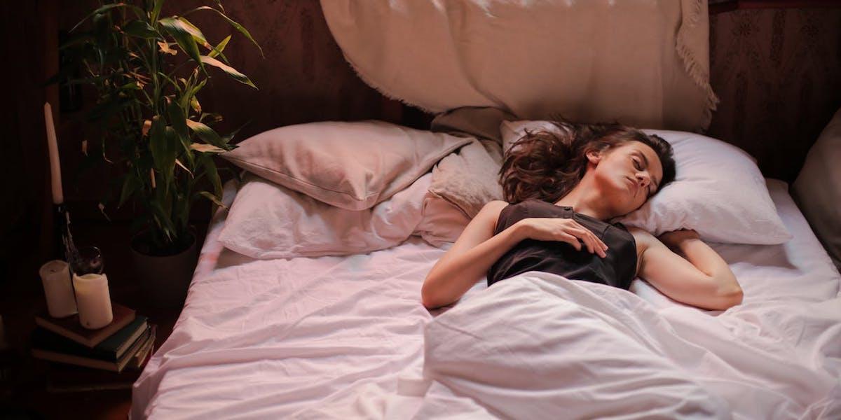 En kvinna sover ensam i en dubbelsäng, experter tipsar om hur du kan somna ensam