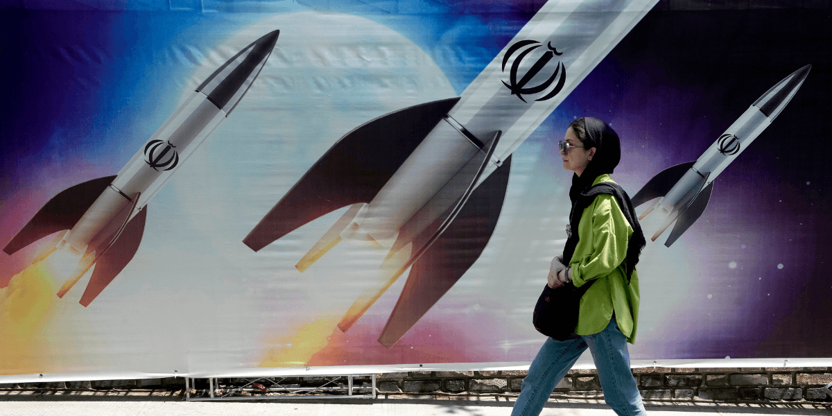 En kvinna går förbi en banderoll som visar hur missiler avfyras i norra Teheran, Iran, den 19 april 2024.