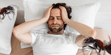 Person upplever obehag och krypningar i benen vid läggdags, symtom på restless legs syndrome (RLS).