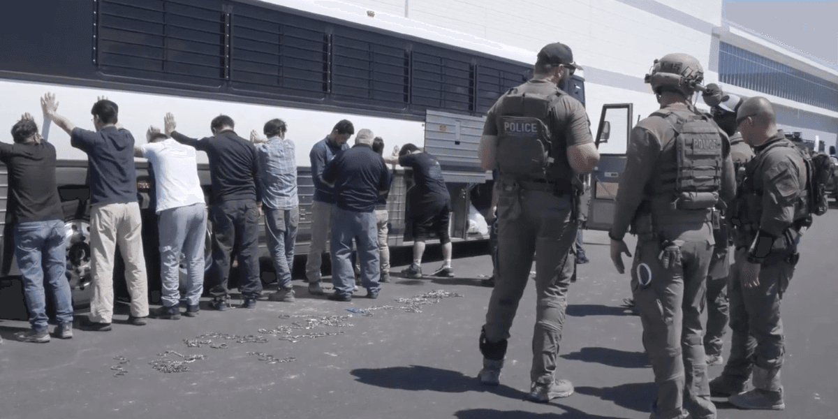 Denna bild från en video från U.S. Immigration and Customs Enforcement via DVIDS visar anställda på en fabrik som väntar på att få sina ben bojade vid Hyundai Motor Groups elbilsfabrik. (Foto: Corey Bullard/AP/TT)