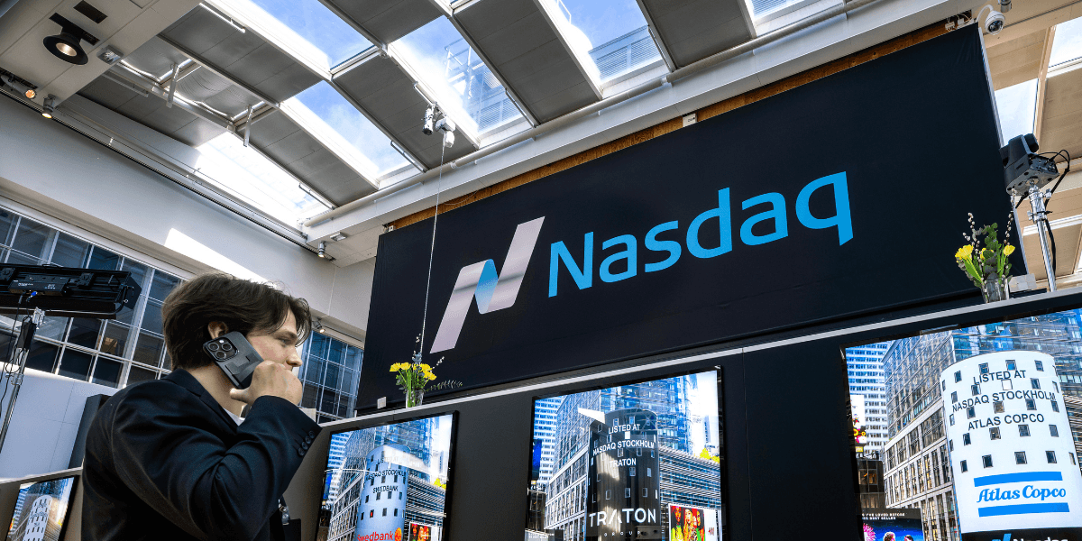 En man på börsen tittar på en skärm där det står Nasdaq.