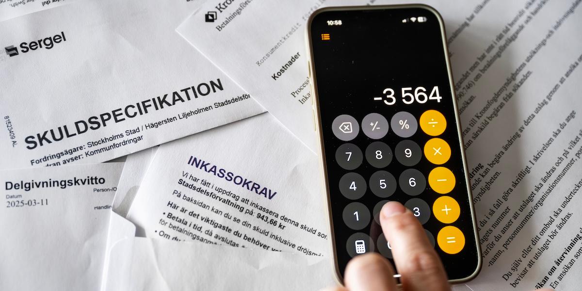 Räkningar och skuldspecifikationer tillsammans med en miniräknare som visar minusbelopp.