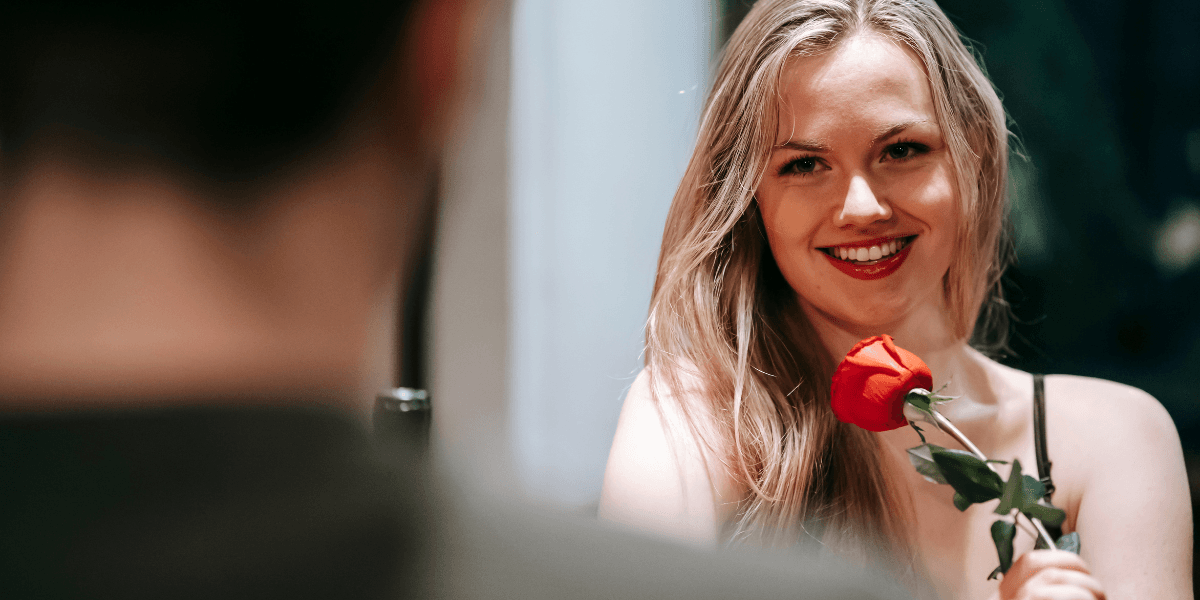 Kvinna på dejt med ros i handen – symboliserar den växande trenden att investera i professionell dejtingcoachning för att hitta en seriös relation.