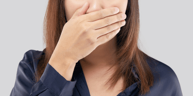 Person som täcker munnen med handen för att illustrera en farlig mening man inte bör säga på en intervju.