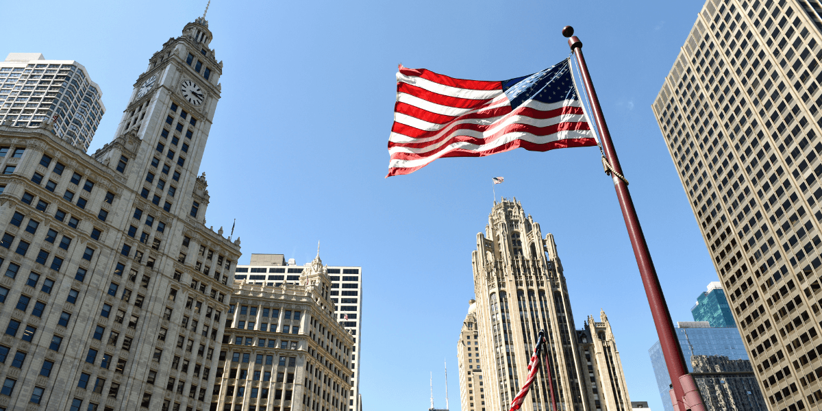 Amerikansk flagga framför höga byggnader i finansdistrikt – inflation och räntor i fokus i USA.