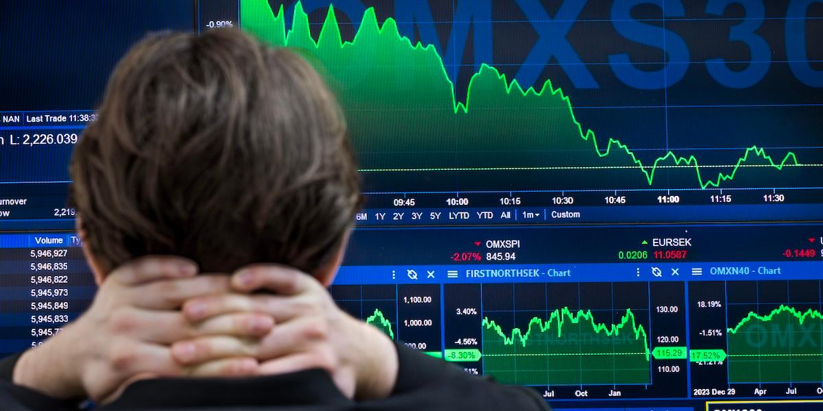 Person tittar på en datorskärm som visar kursfall och grafer för OMXSPI och andra börsindex under 2025.