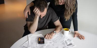 En man och kvinna oroar sig över räkningar på ett bord.