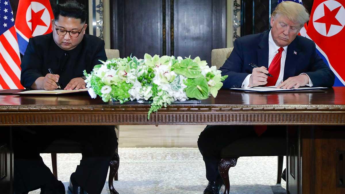 Kim Jong-Un och Donald Trump undertecknar dokument på historiska mötet i Singapore. (Foto: TT)
