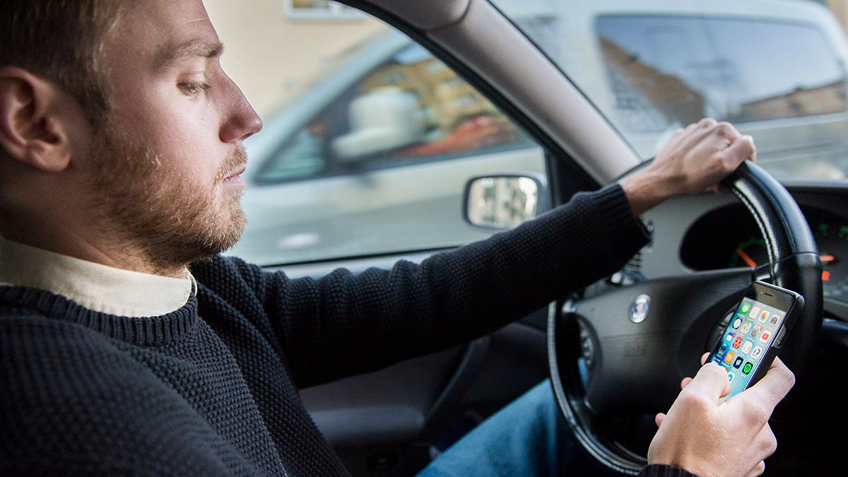 Att sitta med mobilen i handen under bilkörning är olagligt; den skärpta lagen trädde i kraft 1 februari i år. (Foto: TT)