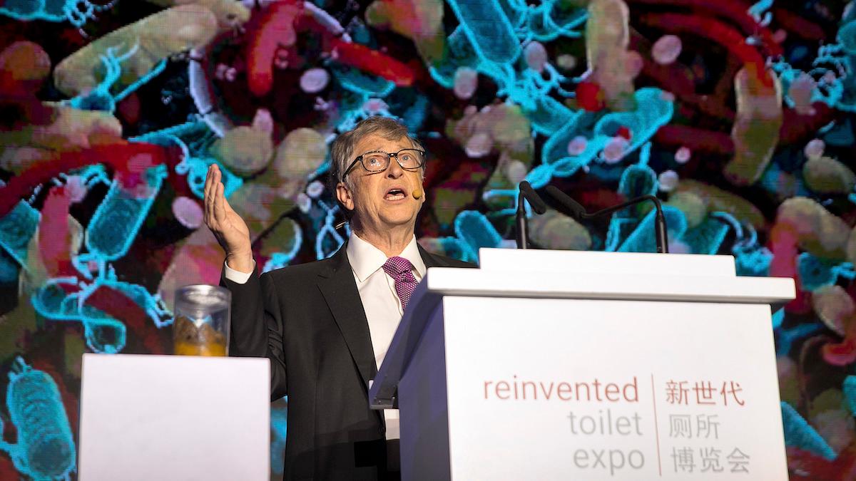 Bill Gates talar med en burk mänsklig avföring på ett podium bredvid sig på Reinvented Toilet Expo i Peking i november 2018