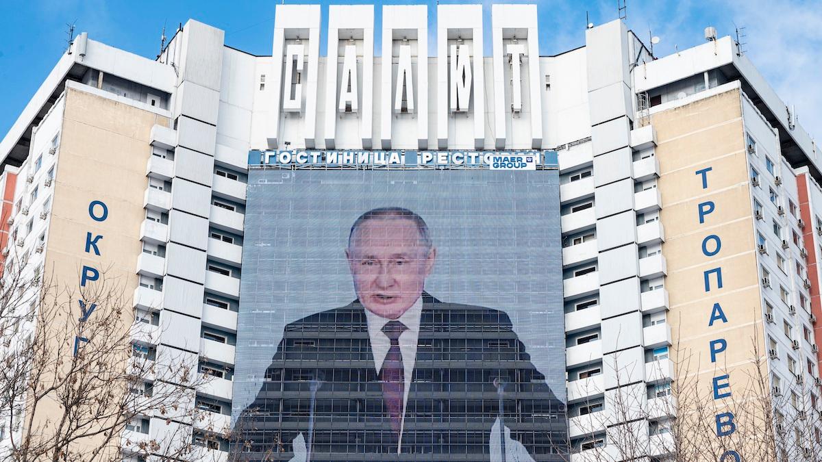 En stor skärm på ett hotell visar Rysslands president Vladimir Putin hålla sitt årliga tal till nationen