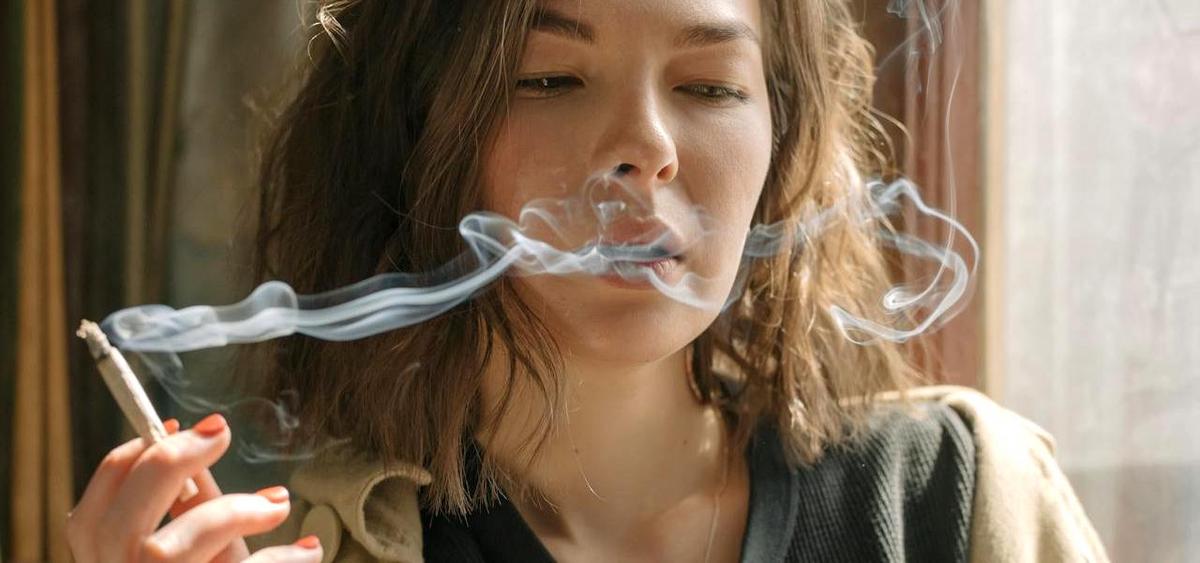 En kvinna röker. Forskare har hittat något som kan förklara varför kvinnor blir beroende av nikotin snabbare än män