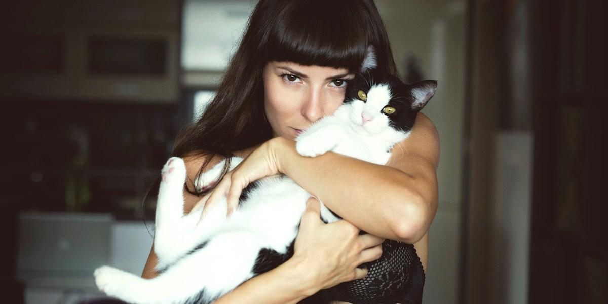 En kvinna kramar en katt. Nivårena av stresshormonet kortisol kan minska av att krama den du älskar
