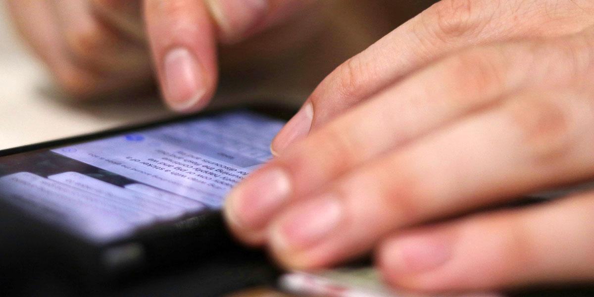 En närbild på en persons händer som håller i en smartphone.