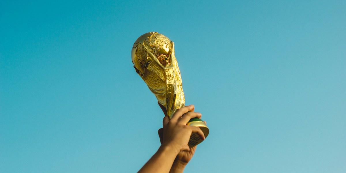 Bild på en trofe som ett par händer håller upp. Att vara en bedragare kan vara framgångsrikt.