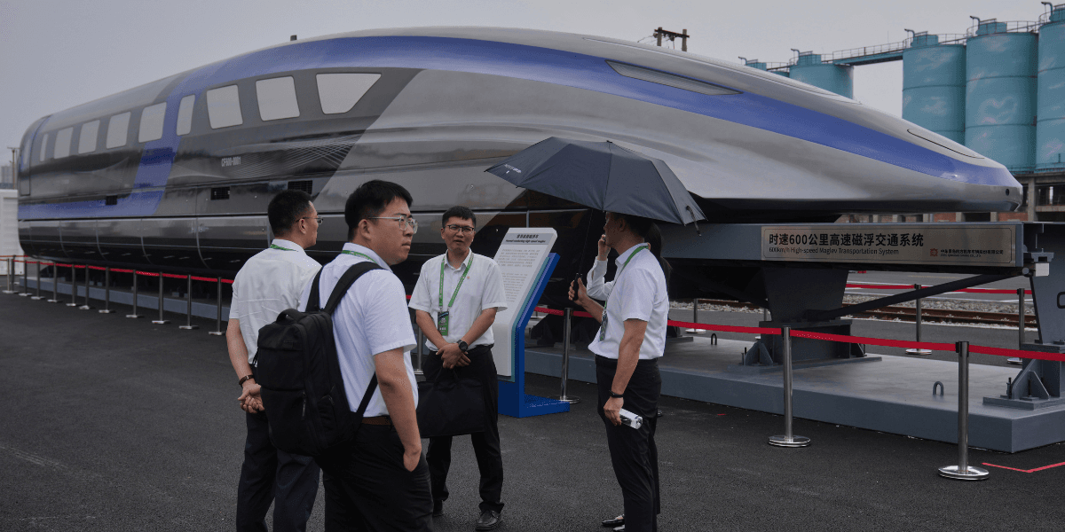 Arbetare pratar nära ett 600km/h höghastighets Maglev-tåg. (Foto: Andy Wong/AP/TT)