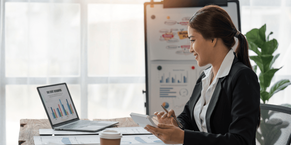 Företagare analyserar ekonomiska rapporter inför årsskiftet, med laptop och grafer på skrivbordet.