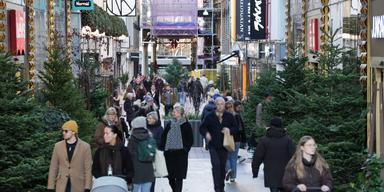 Människor promenerar på julpyntad shoppinggata i november.