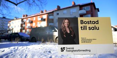 Till salu-skylt från Svensk Fastighetsförmedling framför flerbostadshus i vintermiljö i Sverige.