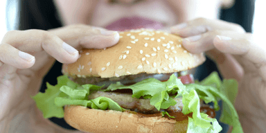 kvinna äter snabbmat.